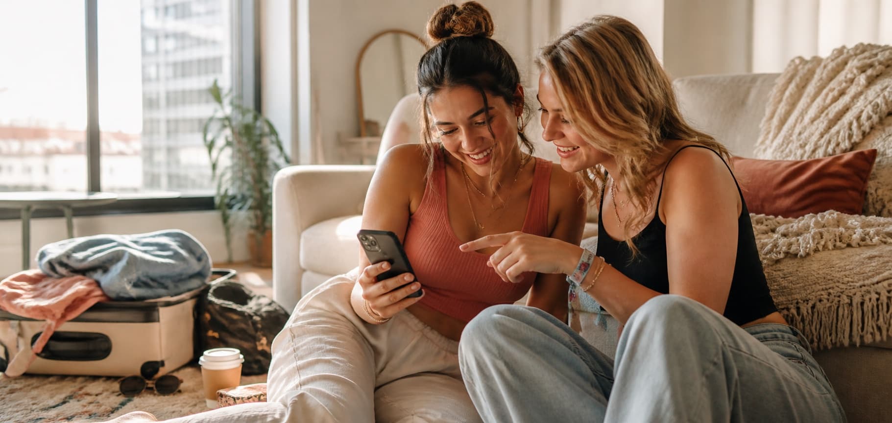 Two friends laughing together while choosing favorite photos from a weekend trip